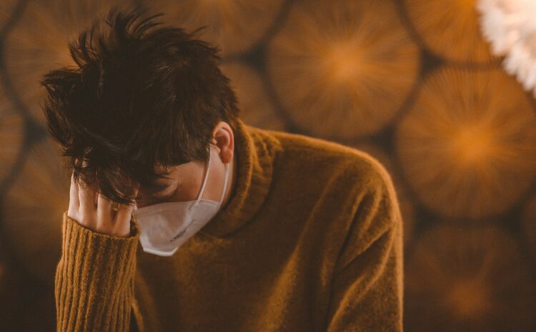 man in brown coat wearing white face mask